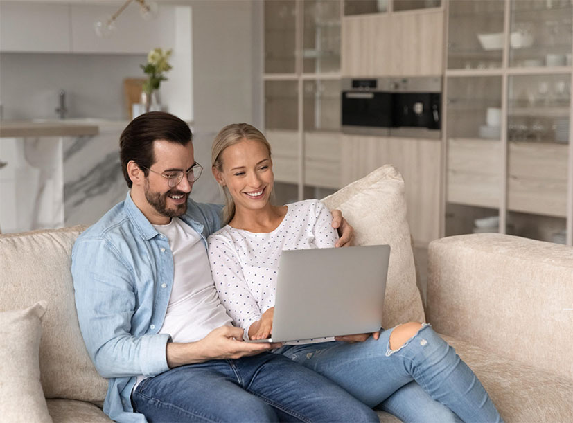 A couple sitting on a lounge chair looking at a laptop