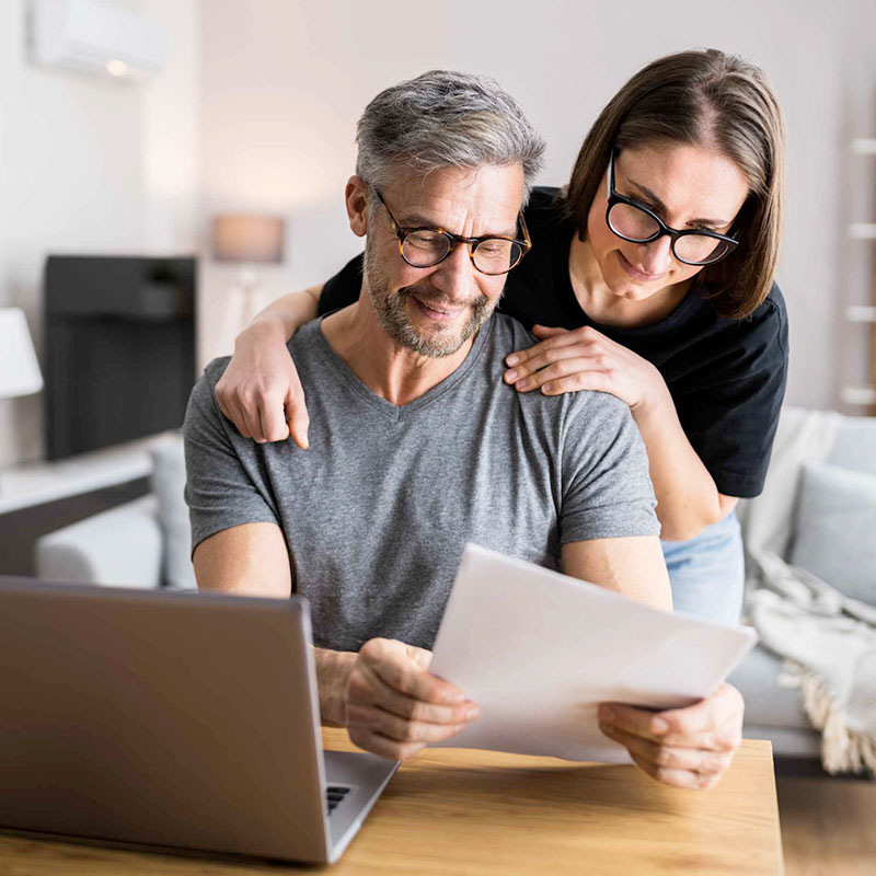 a couple at a desk looking at a printout