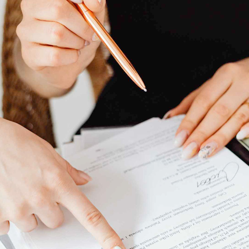 A person with a pencil in hand about to sign a document