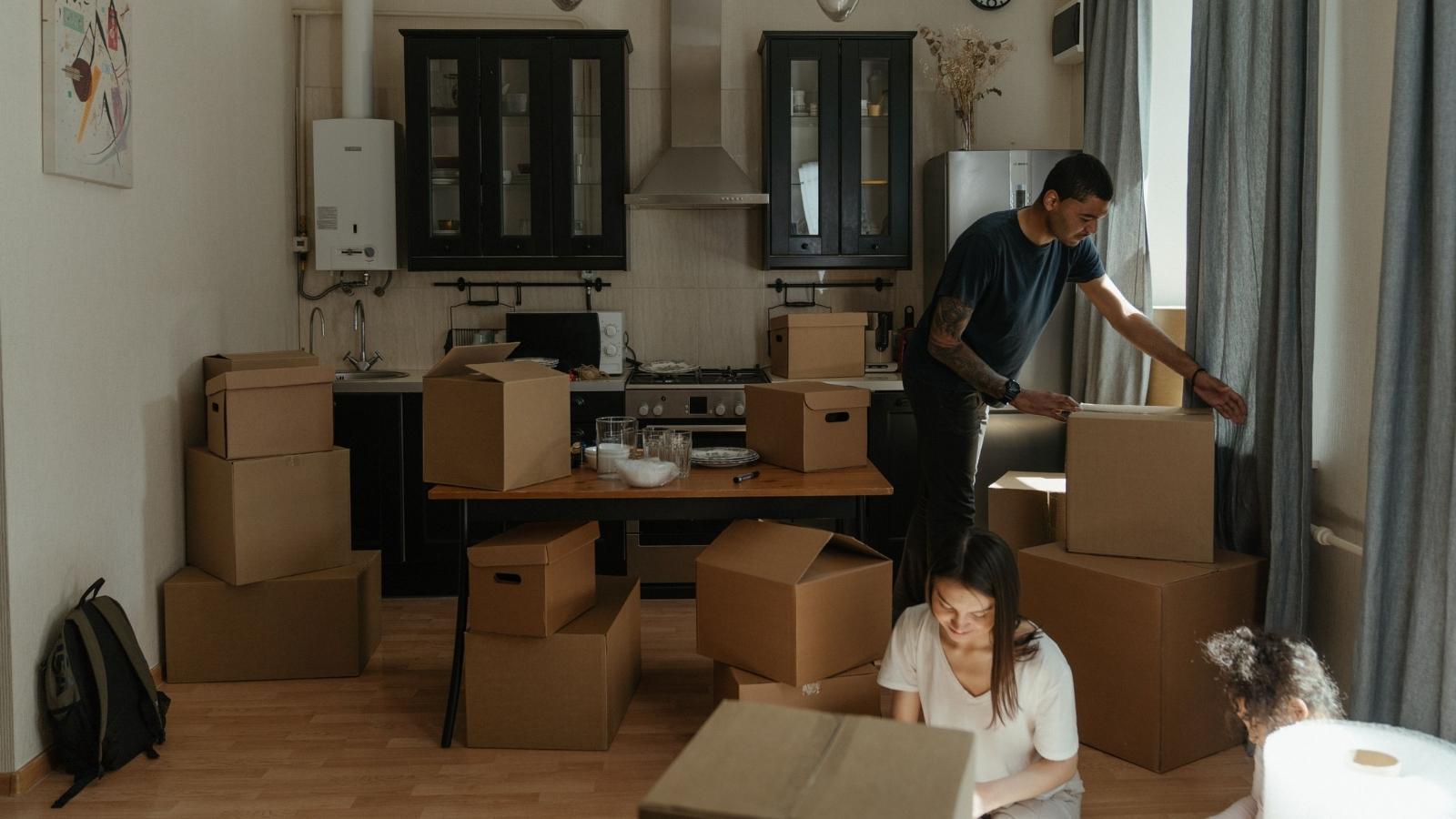 A mother, father and daughter pack their belongings in boxes.