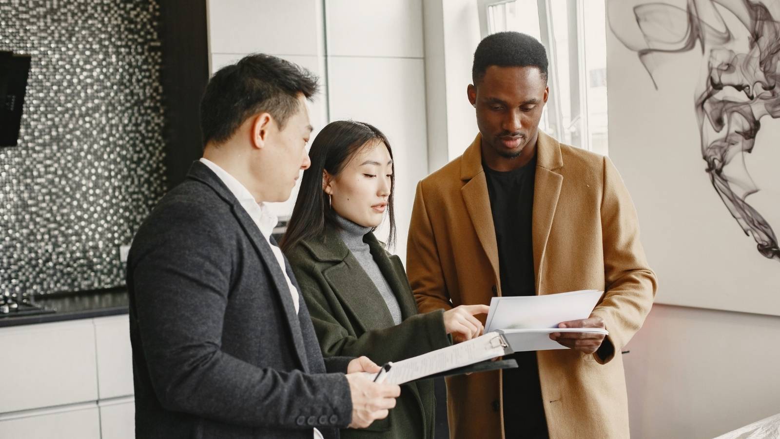 Couple study paperwork with agent