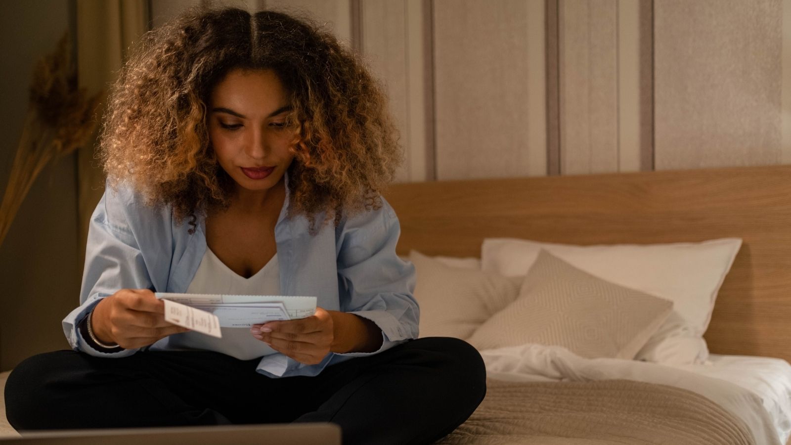 Person reviewing side hustle income, receipts and a household budget on bed.